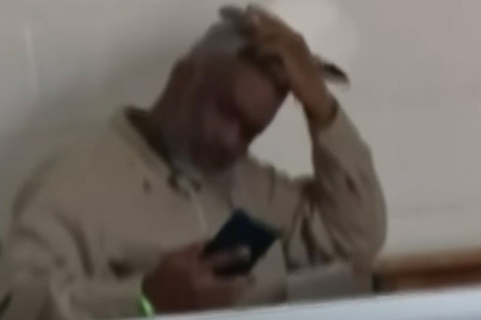 Sean Combs looking down at his phone while holding his hand to his head.